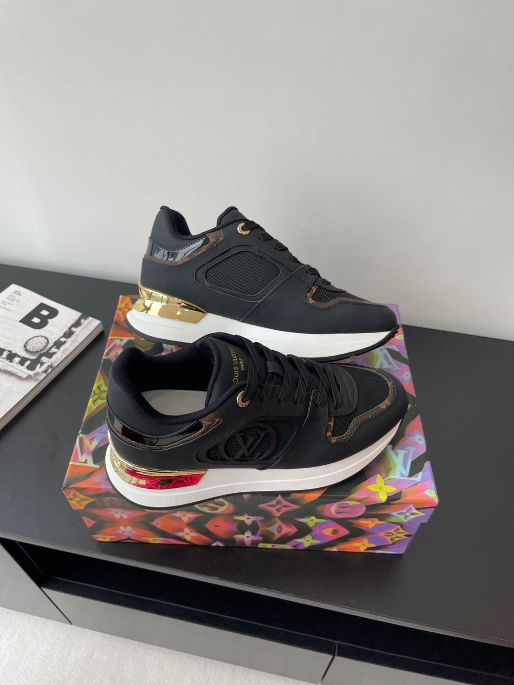 Ladies lace-up sneaker side view, dark upper with gold sole detail and LV logo.