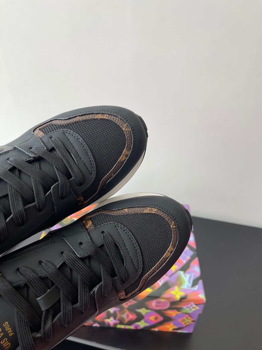 Ladies sneaker close-up, dark laced upper with textured paneling and gold trim edge.