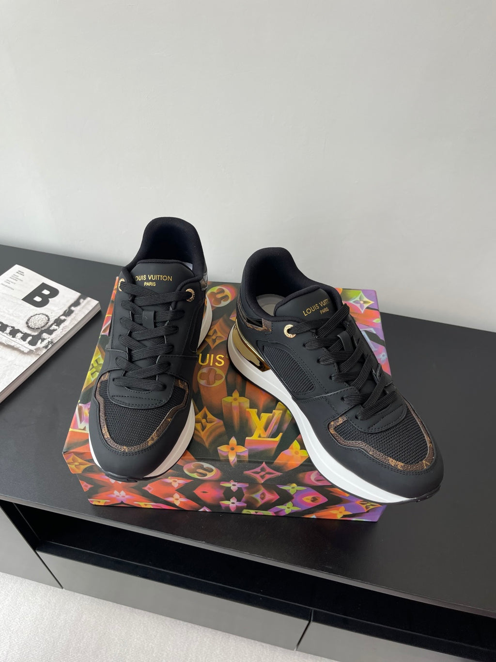 Ladies lace-up sneakers pair, dark upper with gold-accent sole and LV logo on sides.