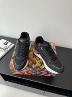 Ladies lace-up sneakers pair, dark upper with gold-accent sole and LV logo on sides.