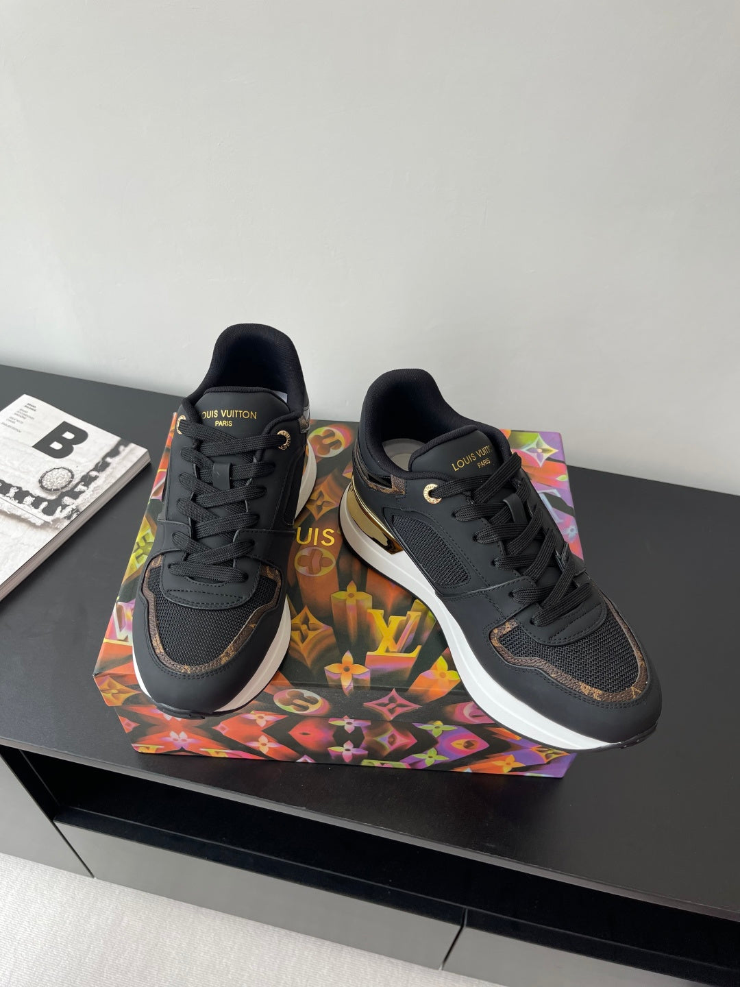Ladies lace-up sneakers pair, dark upper with gold-accent sole and LV logo on sides.