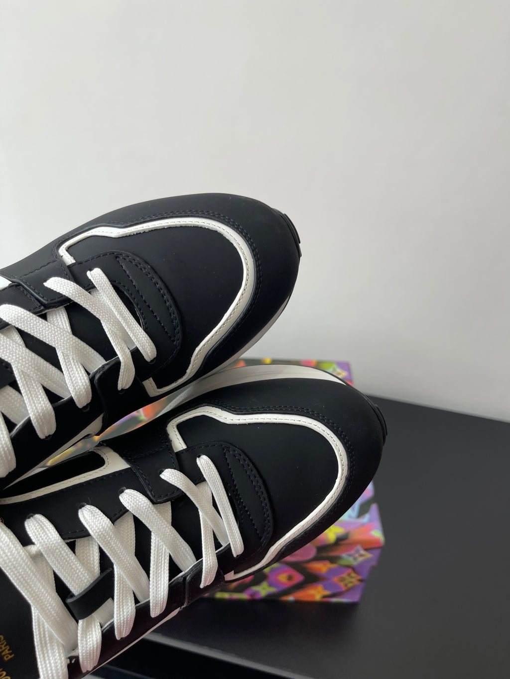 Ladies' Louis Vuitton sneakers close-up, black uppers with white laces and curved trim.