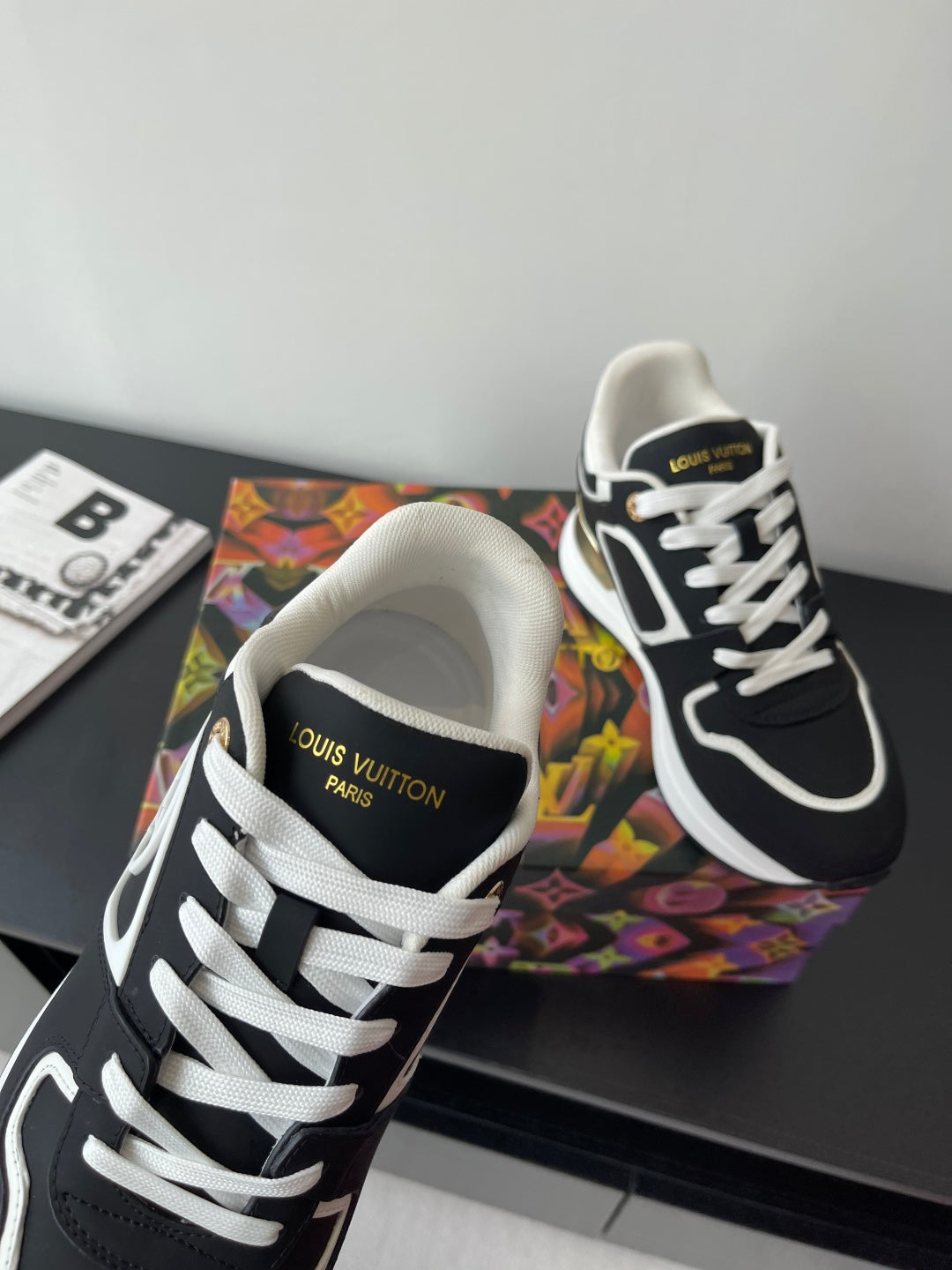 Ladies' Louis Vuitton sneakers close-up, black with white laces and gold heel accent.
