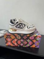 White Louis Vuitton sneakers with black piping, gold detail, and side logo