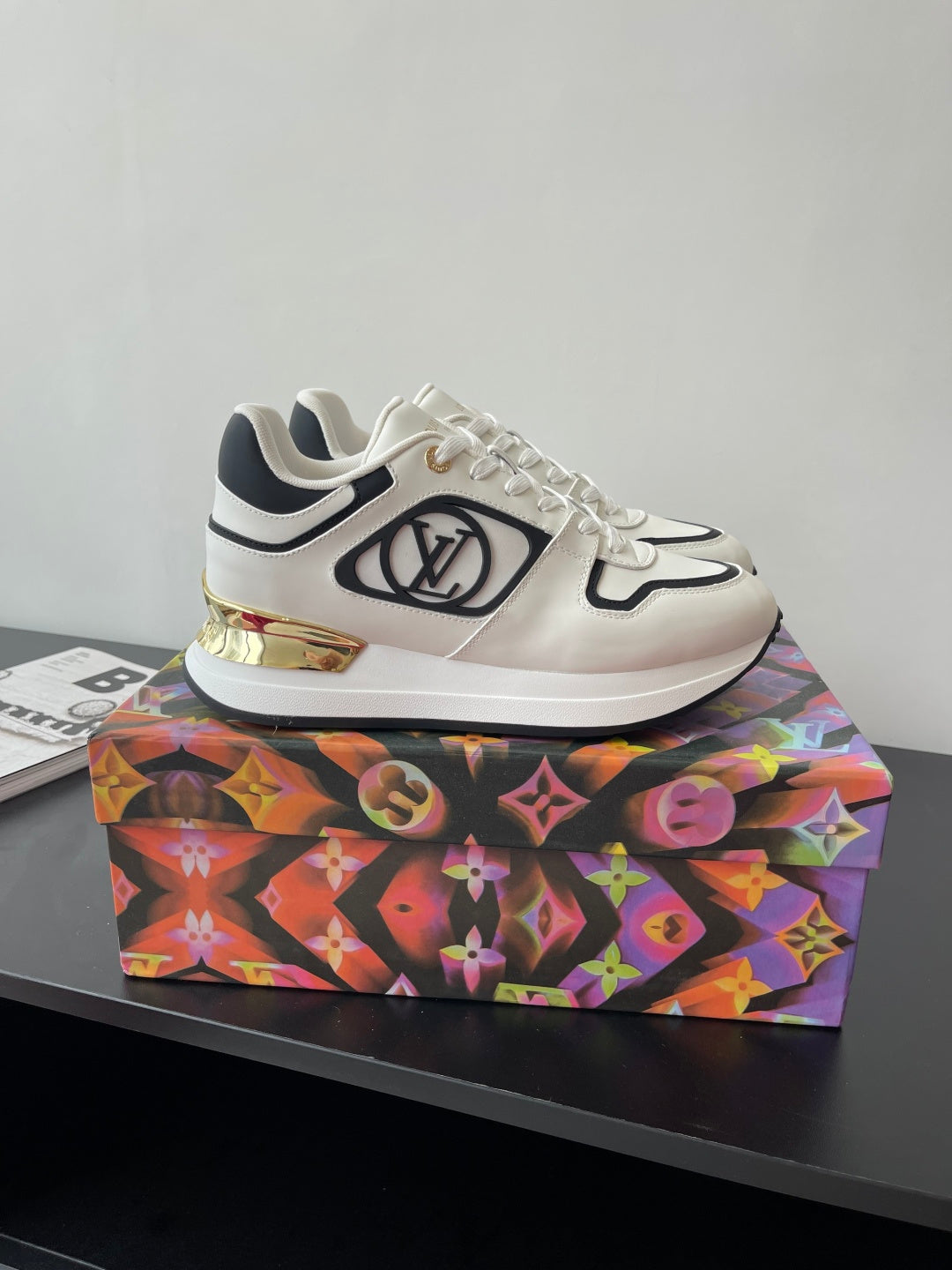 White Louis Vuitton sneakers with black piping, gold detail, and side logo