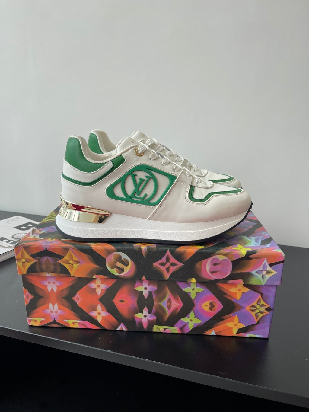 Louis Vuitton women's sneakers, side view; white uppers with green logo panel.