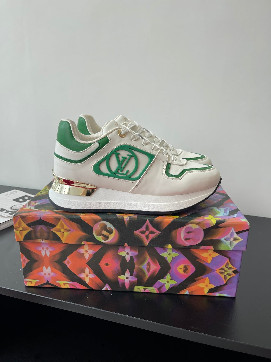 Louis Vuitton women's sneakers, side view; white uppers with green logo panel.