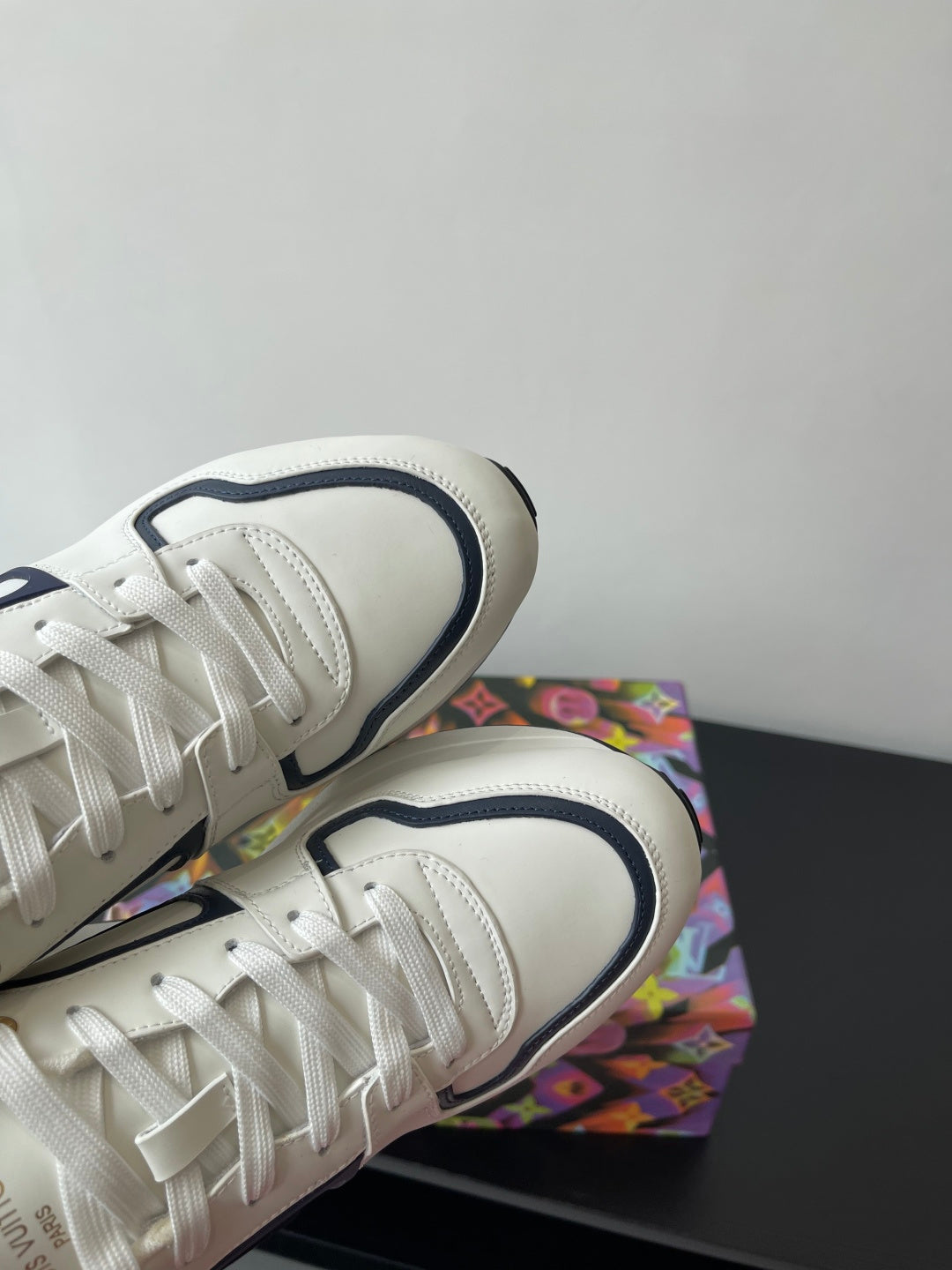 Close-up of white lace-up sneakers with navy-edged collar