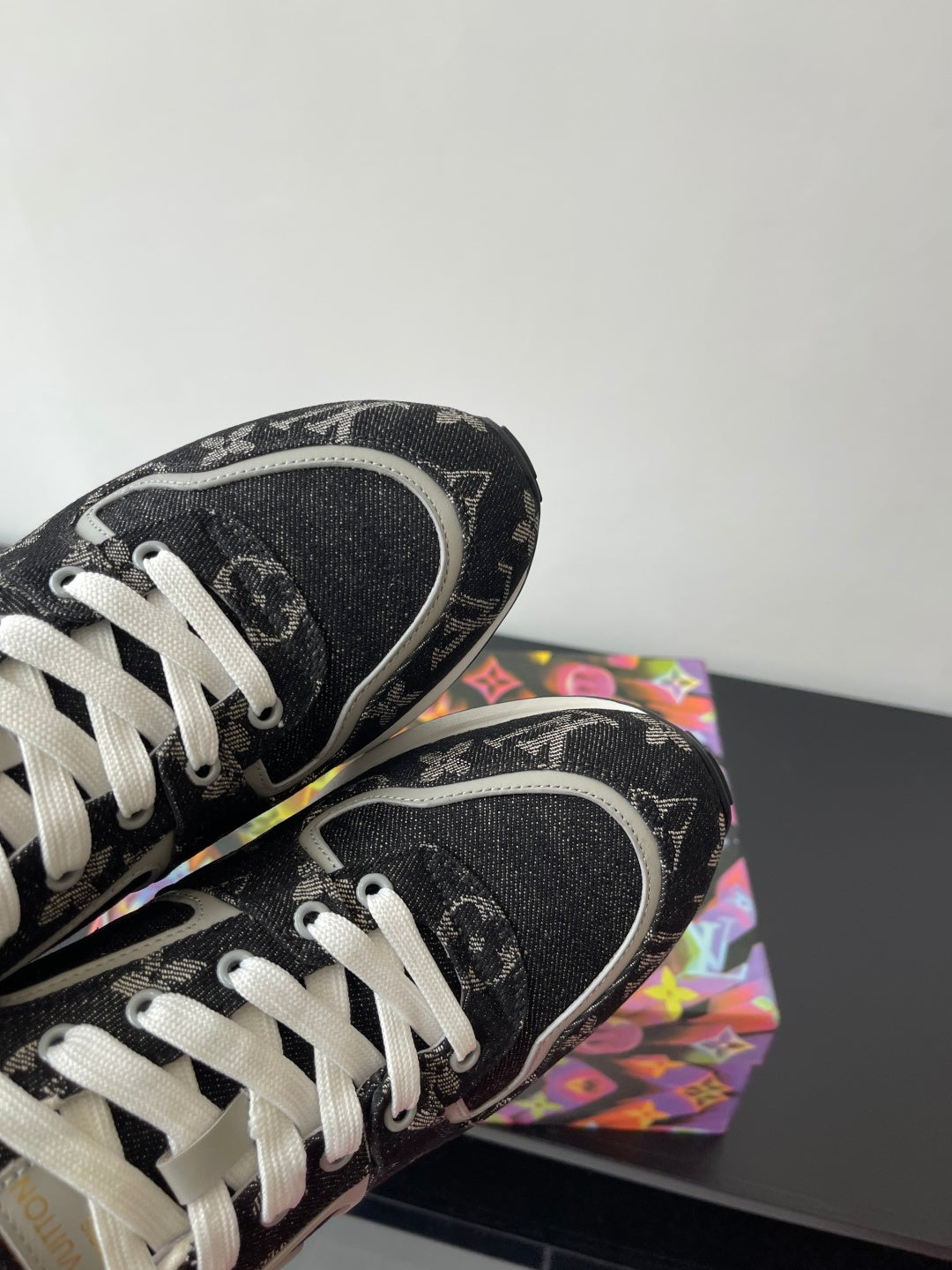 Sneakers toe and side close-up, black textured monogram, white laces, white edge trim