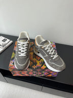 Gray lace-up sneakers with patterned upper and white laces on patterned box