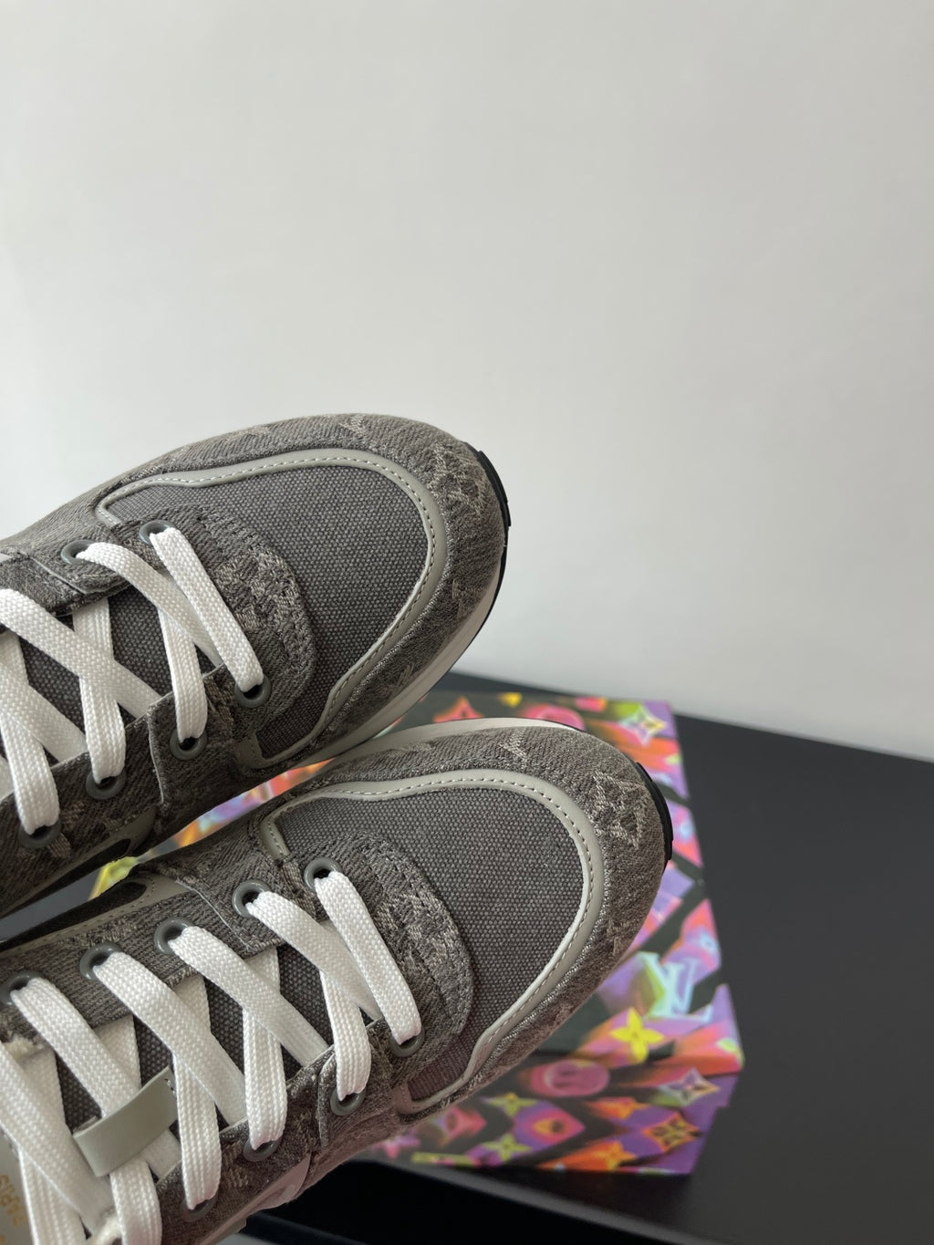 Gray sneakers with white laces; close-up of toe and textured heel panel