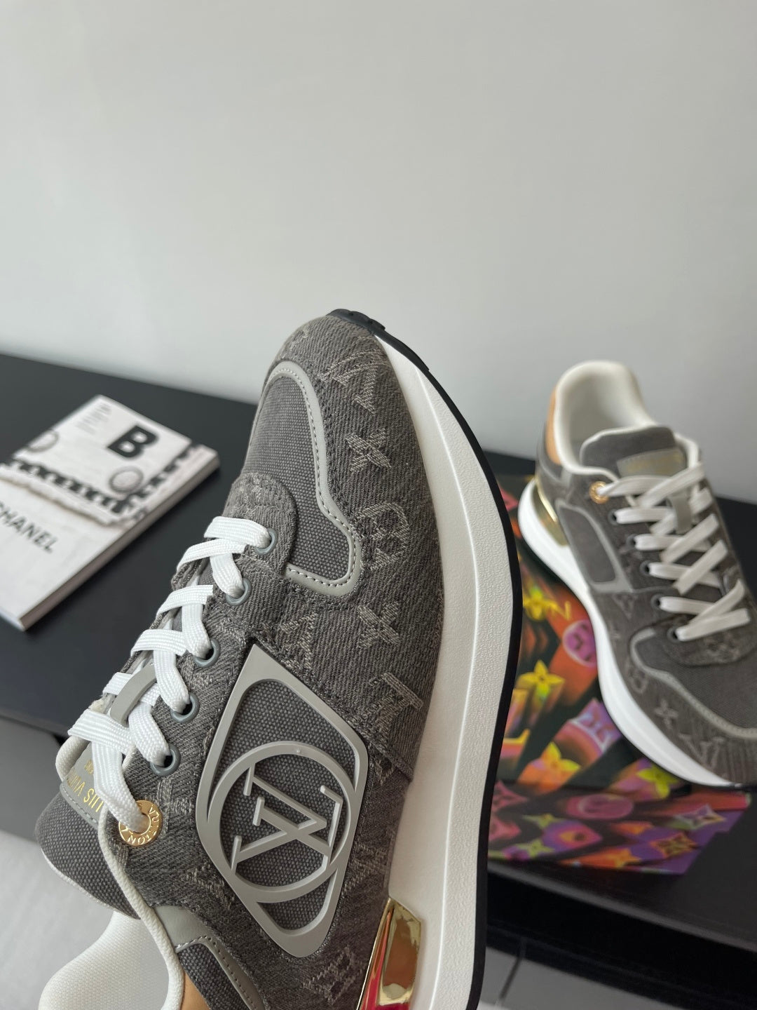 Gray low-top sneaker with side emblem and white laces; angled view
