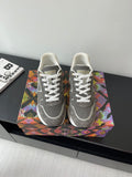Gray low-top lace-up sneakers with patterned panels and white stripe accents