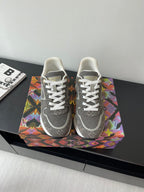 Gray low-top lace-up sneakers with patterned panels and white stripe accents