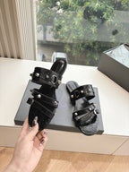 Black strappy slide sandal held by hand, silver buckle hardware, open toe