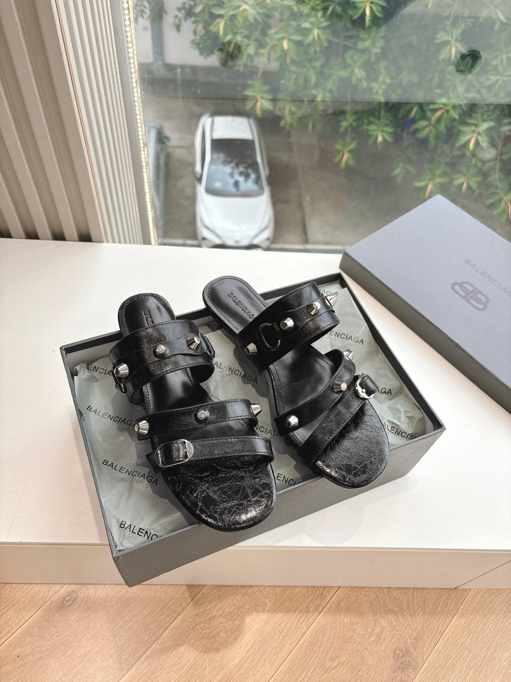 Black leather slide sandals with double straps and silver buckle hardware, open toe