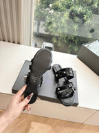 Black slide sandals with silver buckle hardware, side view and footbed