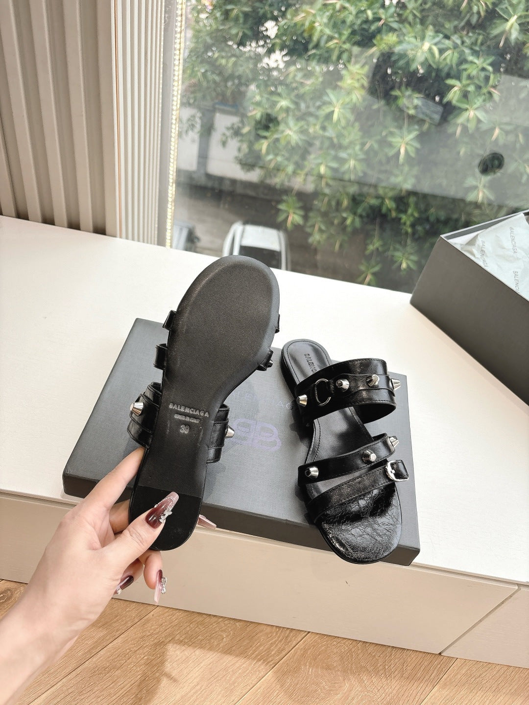 Black slide sandals with silver buckle hardware, side view and footbed