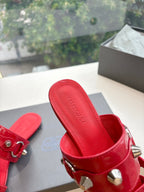 Red slide sandal with silver studs, buckle strap, and Balenciaga logo on footbed