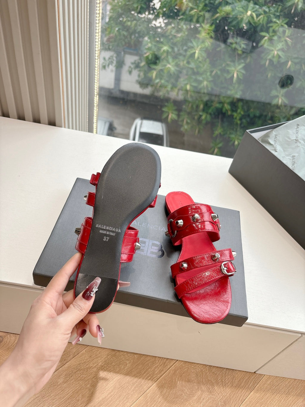 Red slide sandals with metal-studded straps and flat outsole underside