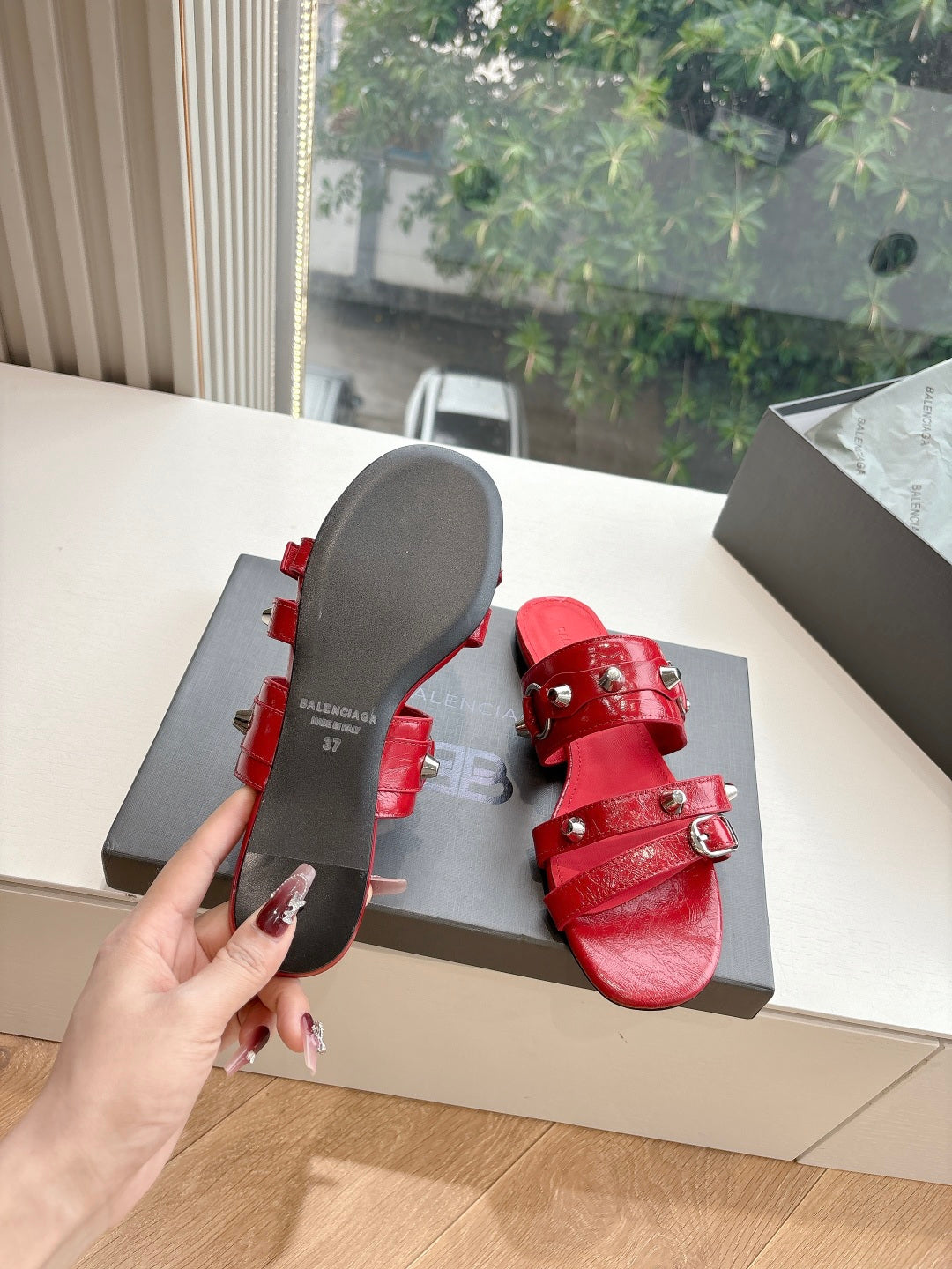 Red slide sandals with metal-studded straps and flat outsole underside