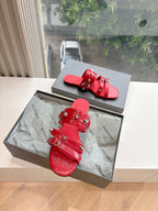 Red strappy slide sandals with buckles and decorative metal studs