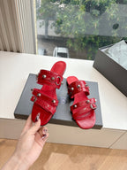 Red slide sandals with thick straps, buckles, and metal studs