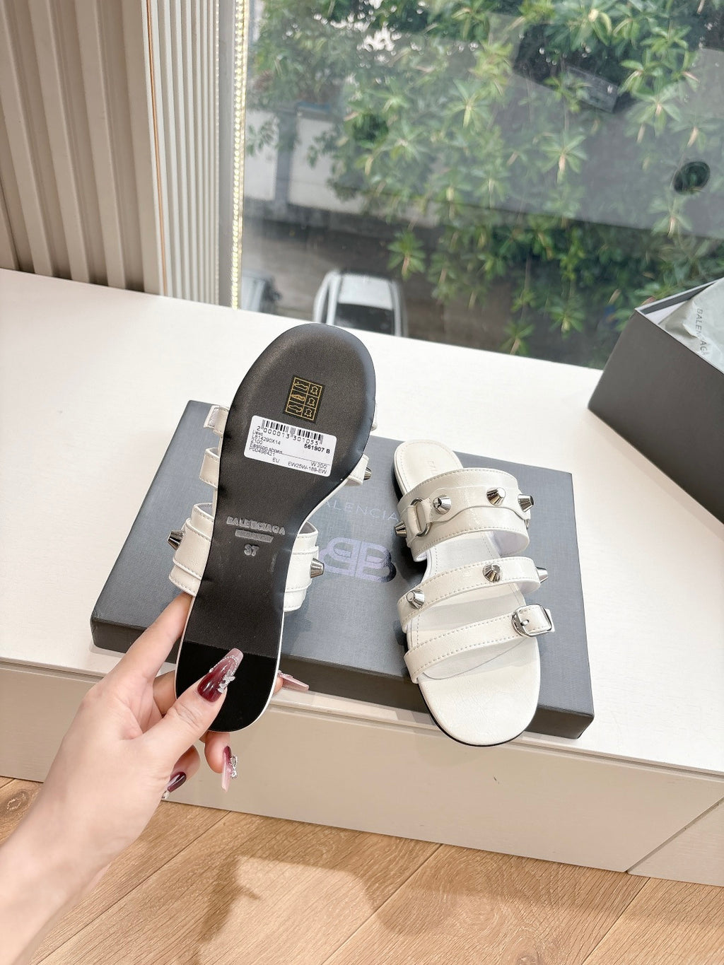 White Balenciaga slide sandals with one visible buckle strap and dark outsole underside