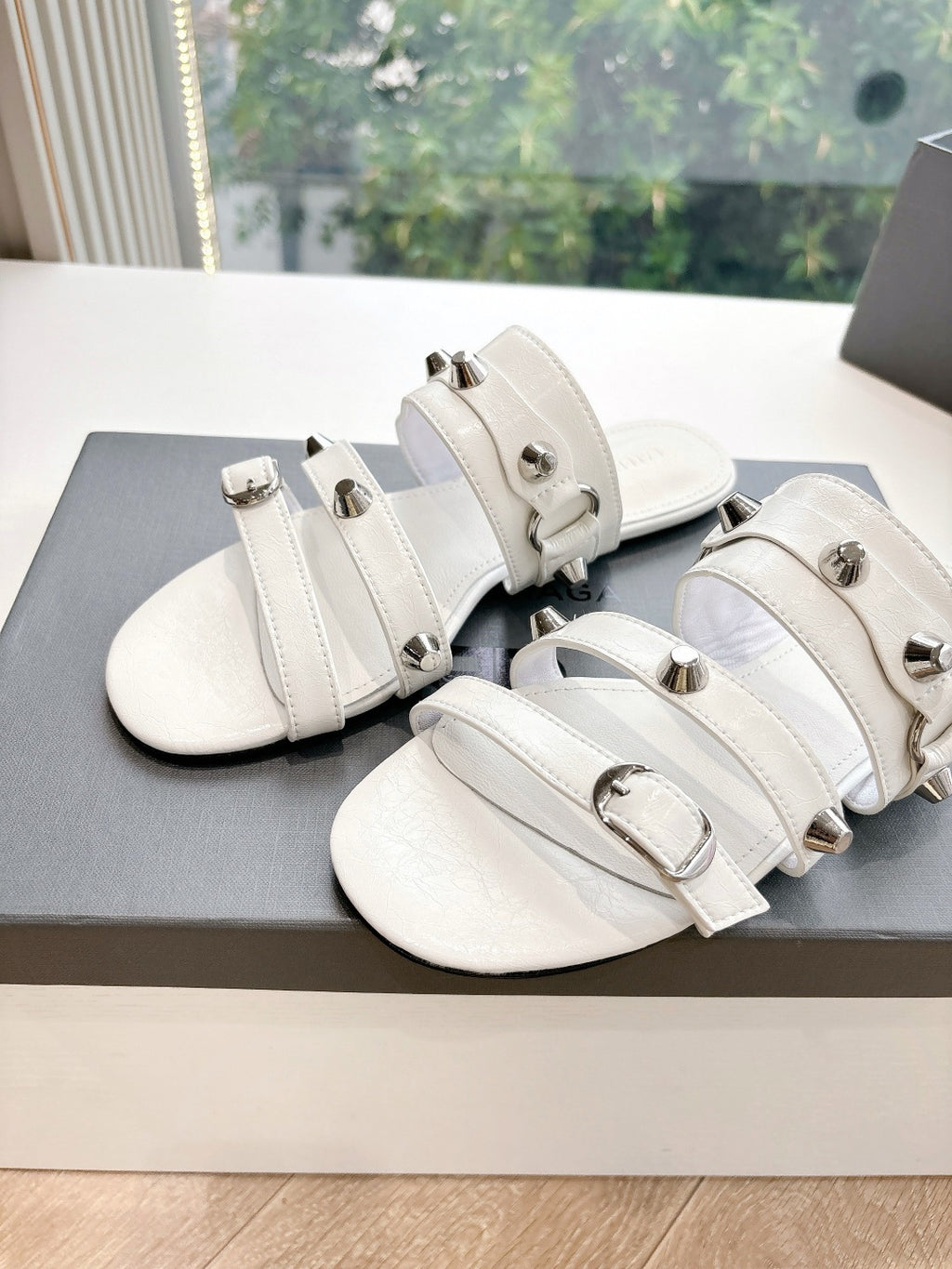 Close-up of white Balenciaga slide sandals with multiple straps and gold-tone hardware