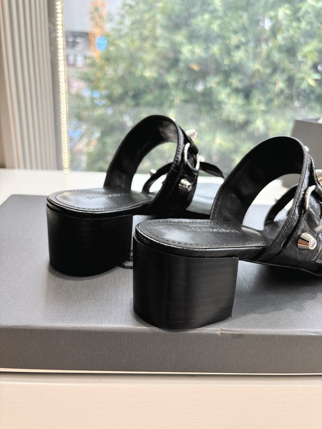 Black leather slide sandals with wide straps and chunky block heels, side angle