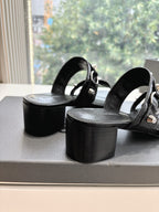 Black leather slide sandals with wide straps and chunky block heels, side angle