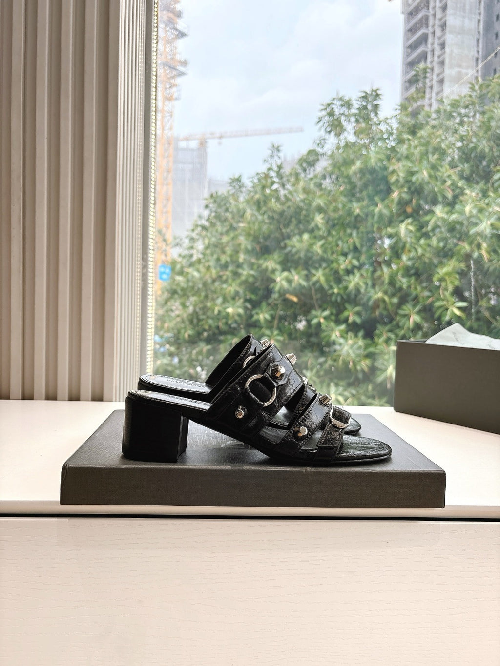 Black leather slide sandal with studded buckles and block heel, side view