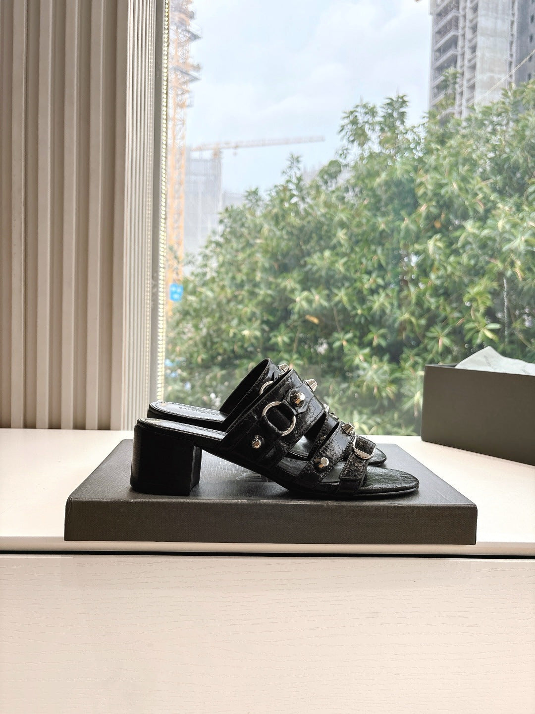 Black leather slide sandal with studded buckles and block heel, side view