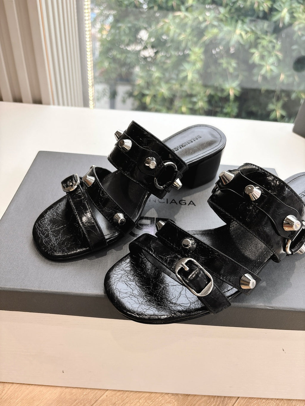 Black leather slide sandals with silver buckle hardware and stud accents
