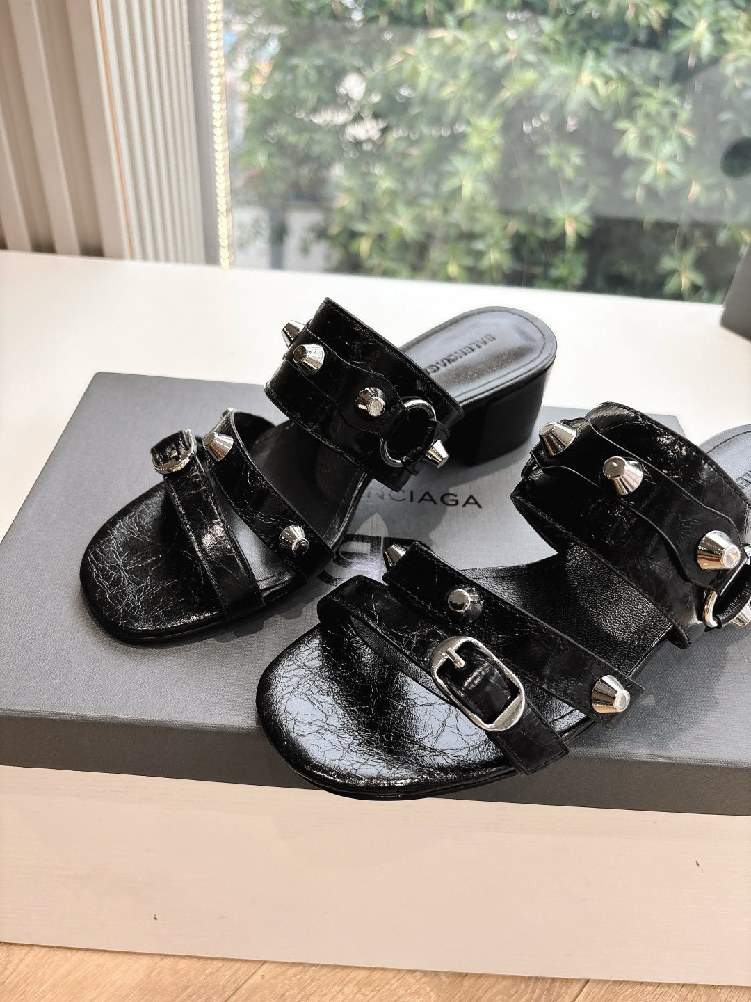 Black leather slide sandals with silver buckle hardware and stud accents