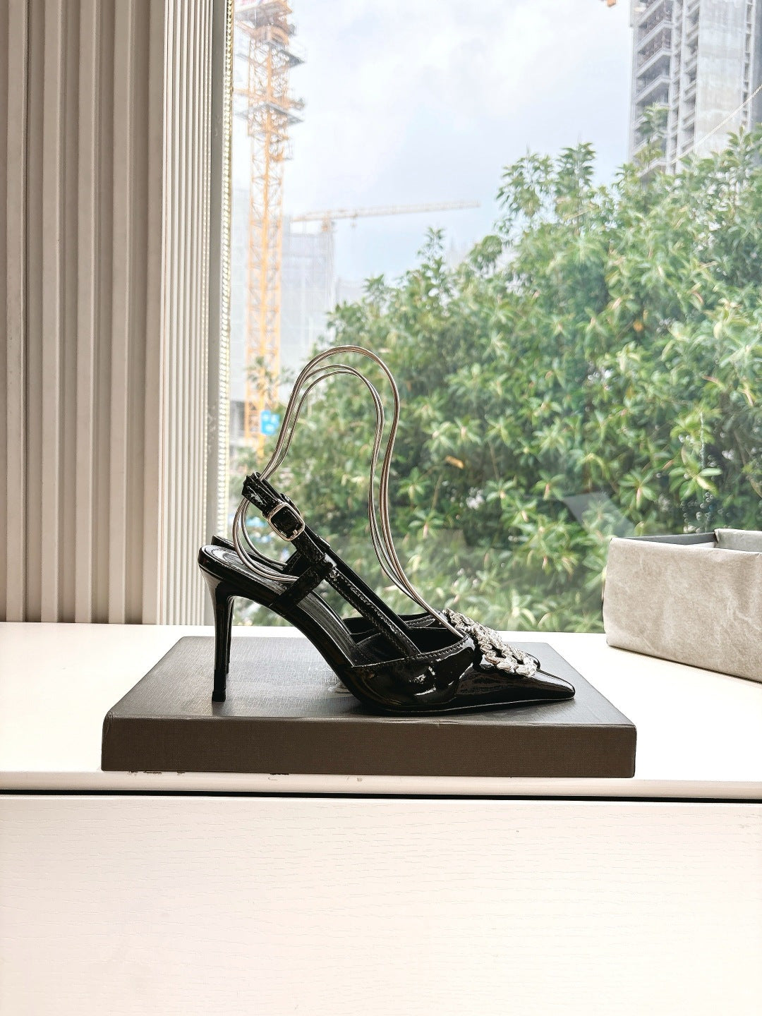 Women's black patent slingback heels with silver jeweled square buckle on box
