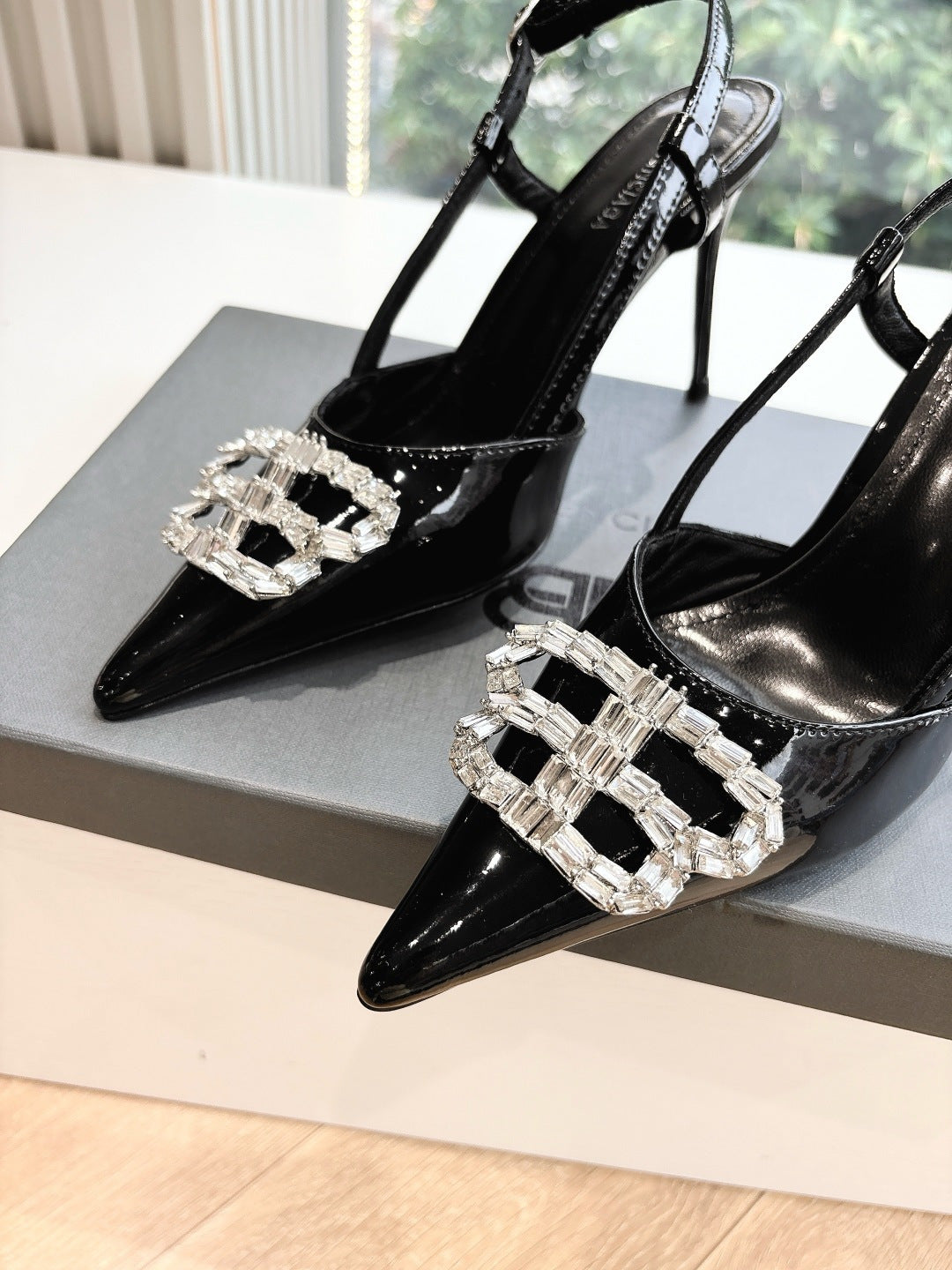 Women's black patent slingback heels with silver jeweled square buckle, close-up