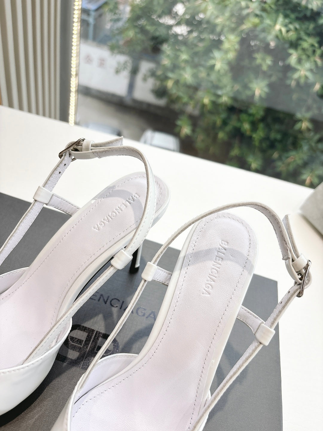 Close-up of women's white slingback heels, showing straps and silver toe buckle