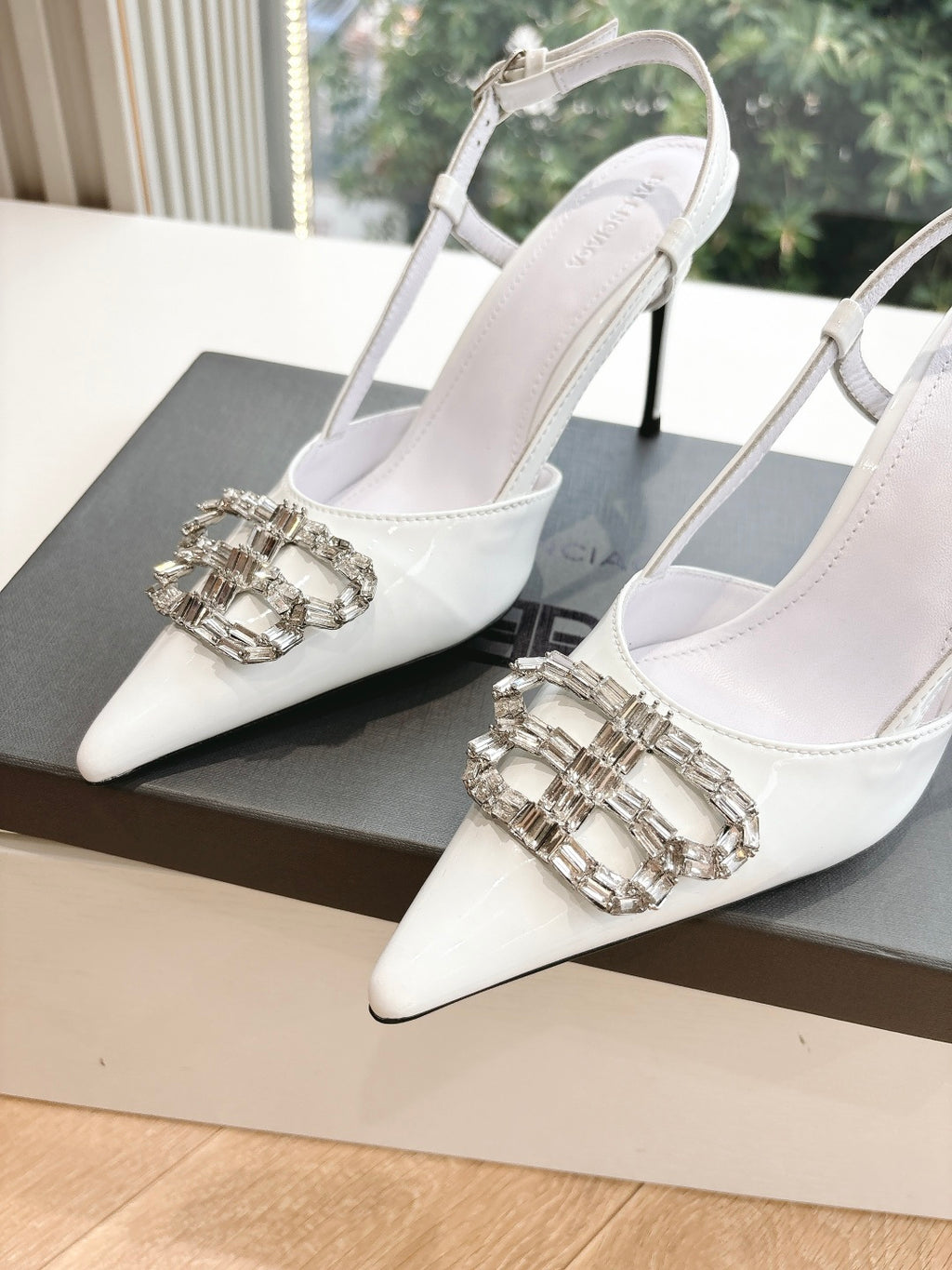Pair of women's white slingback heels with silver jeweled buckle detail on toe