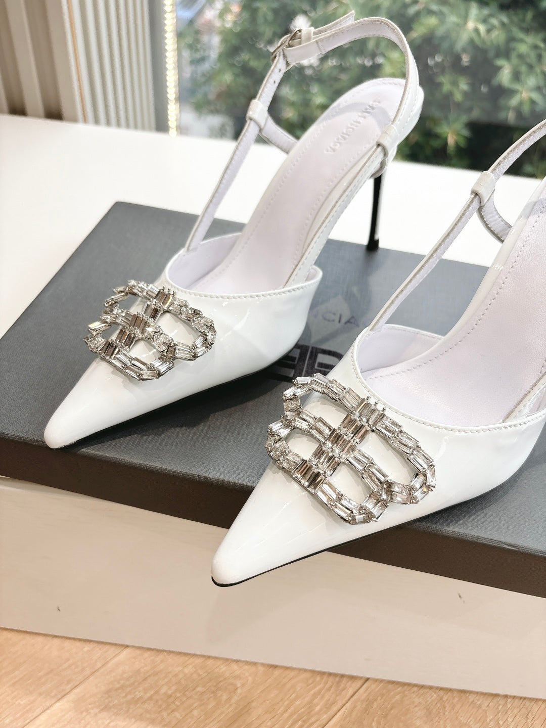 Pair of women's white slingback heels with silver jeweled buckle detail on toe
