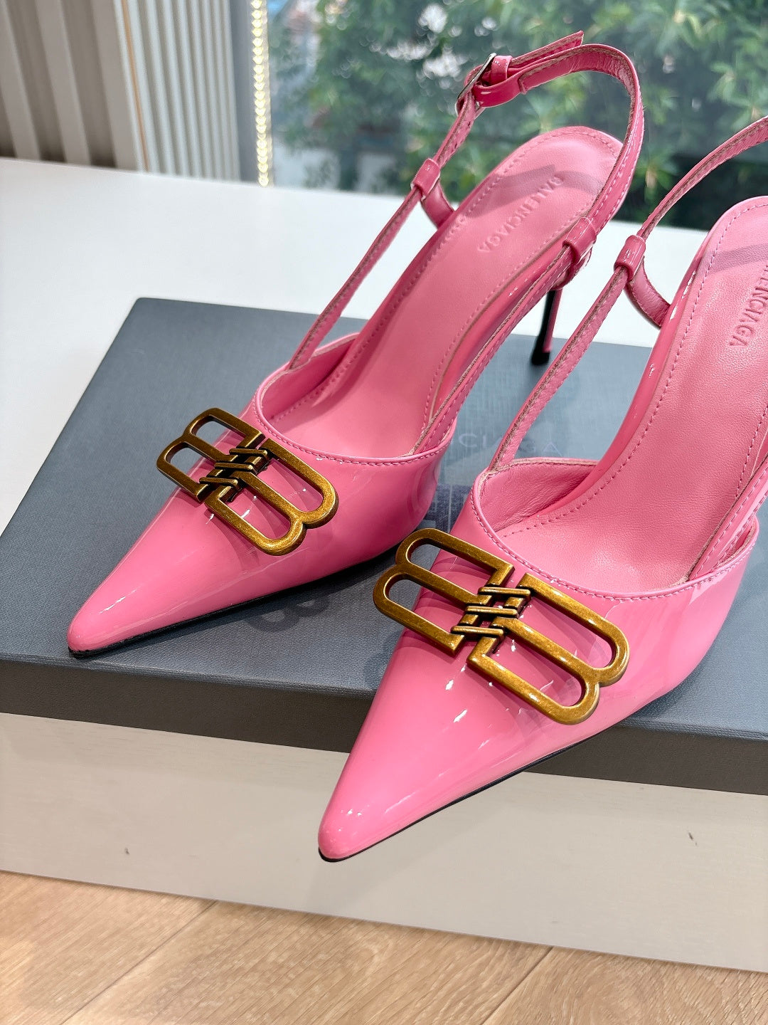 Close-up of pink patent slingback heels with gold buckle and pointed toe