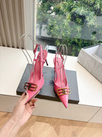 Pink slingback heels with gold buckle ankle strap and pointed toe, held up