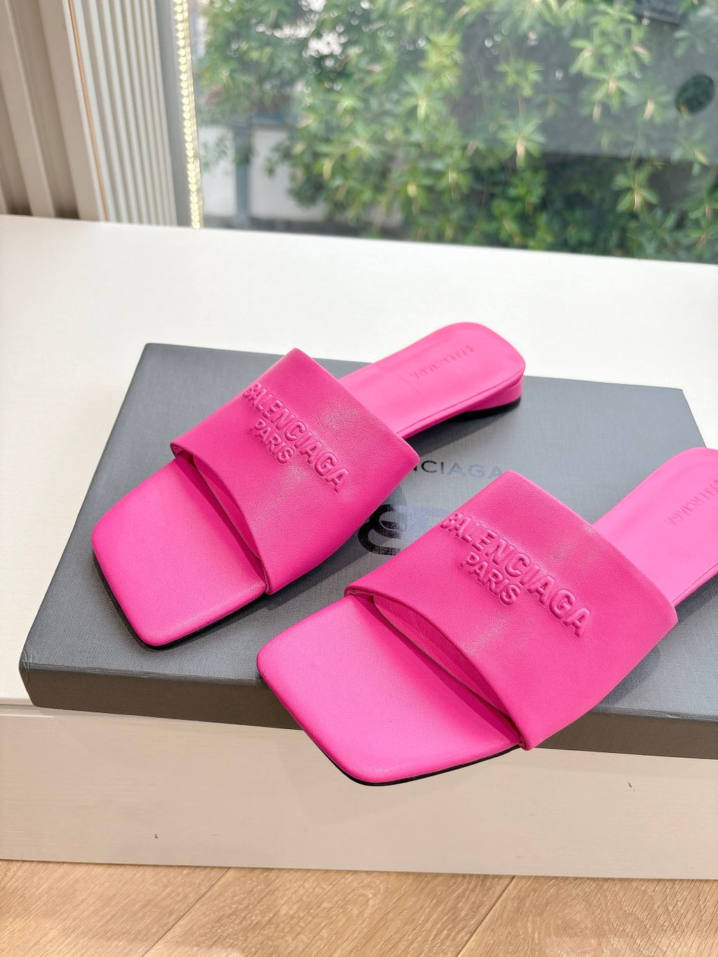 Pink Balenciaga slide sandals with wide straps, embossed logo, open toe.