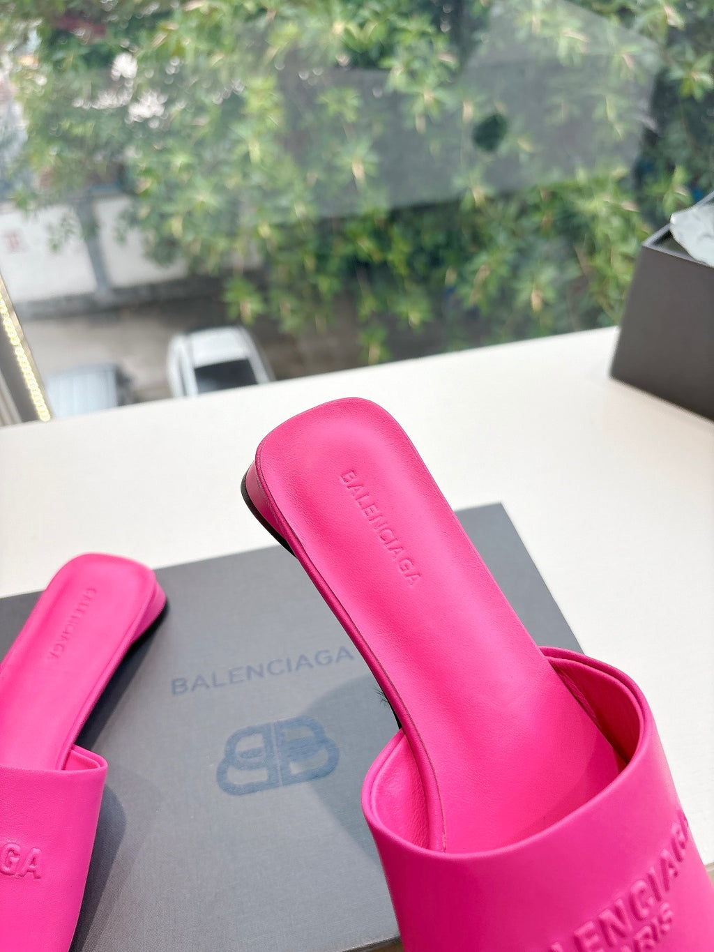 Pink Balenciaga slide sandals close-up, embossed logo on footbed and strap.