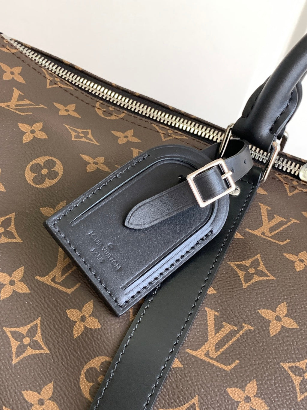 Monogram duffel bag close-up of black leather handle and tag pocket