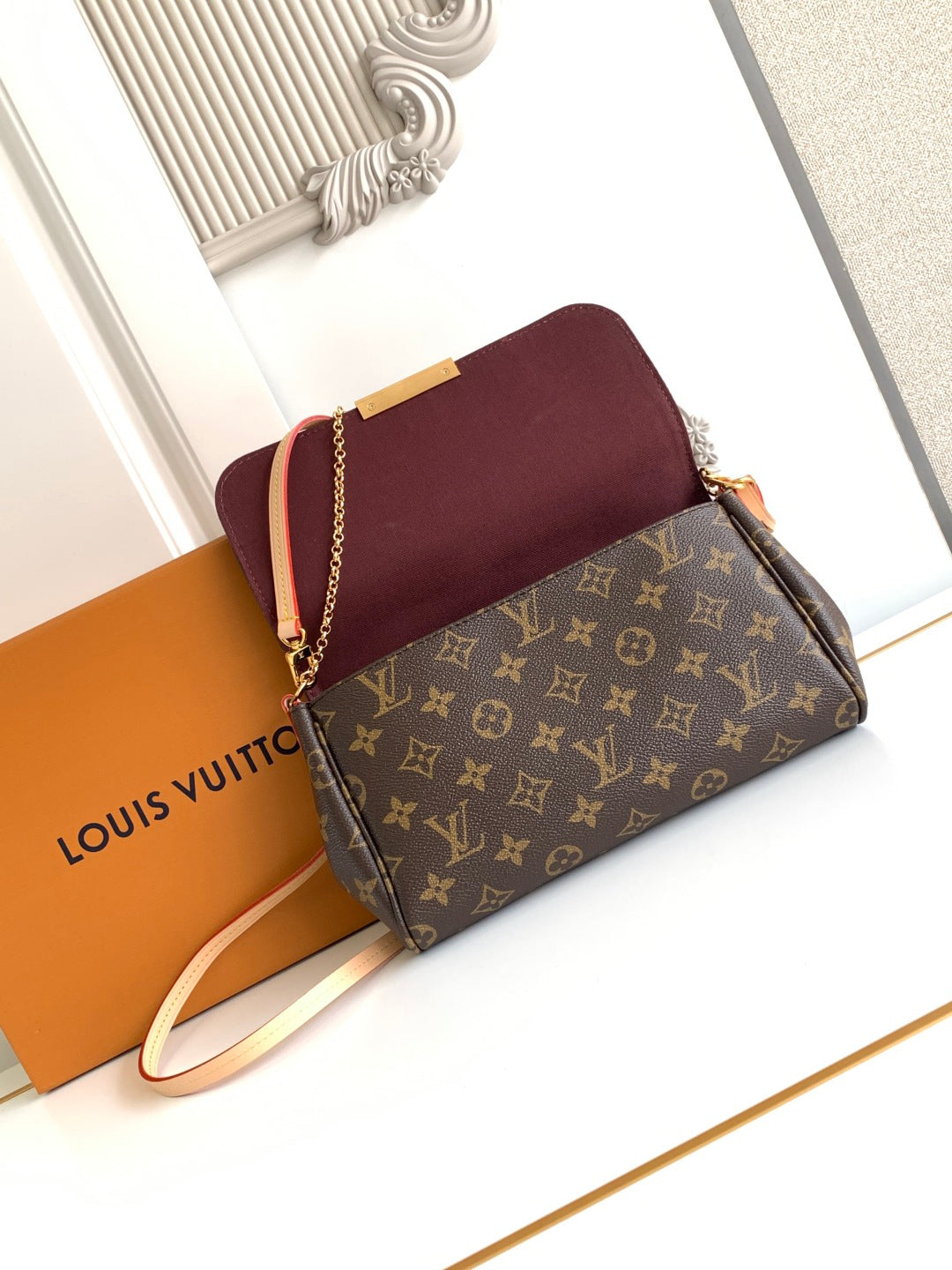 Louis Vuitton crossbody bag with maroon flap, monogram front panel, gold chain strap.