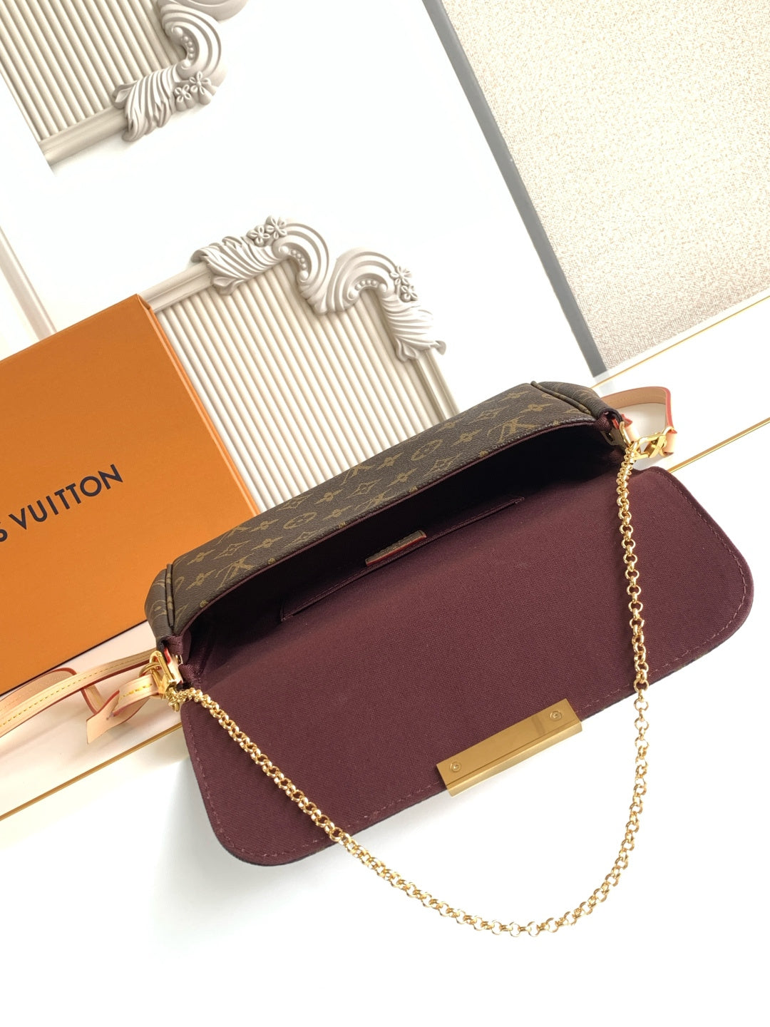 Louis Vuitton maroon flap crossbody bag with monogram top panel and gold chain strap.