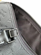 Louis Vuitton monogram bag close-up, gray leather with buckle strap and zipper edge.