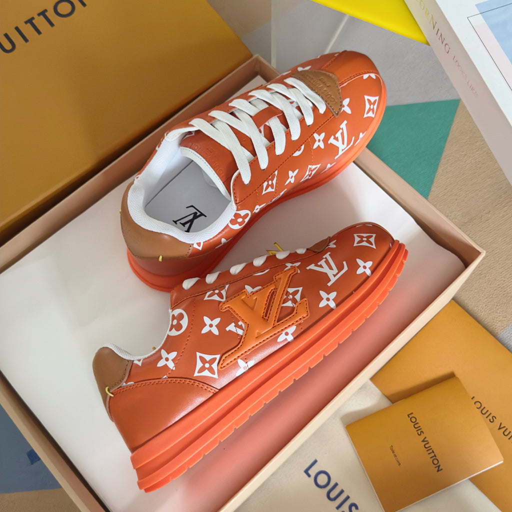 Orange monogram sneakers with white laces and orange rubber sole, side view