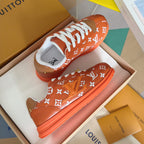 Orange monogram sneakers with white laces and orange rubber sole, side view